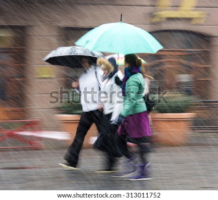 People walking in the street in a snowy winter day in motion blur