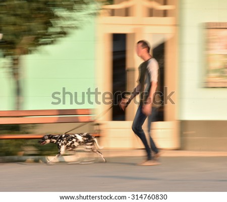 Man walking the dog on the street. Intentional motion blur