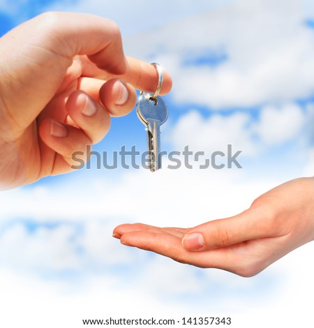 Key in hand over blue sky background.