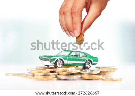 Buying car. Green car and coins over light background.