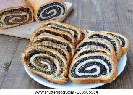 Sliced poppy seed and walnut rolls on wooden table.