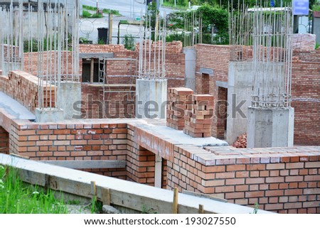 Red brick masonry and reinforced concrete pillars on house under construction.