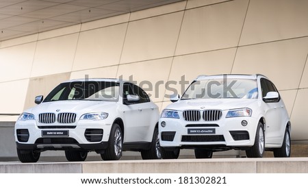 MUNICH, GERMANY - SEPTEMBER 28, 2012: New models of X3 X6 SUV against modern design building. Two white cars on podium wet after rain.