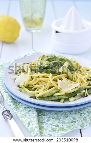 Zucchini Spaghetti alla chitarra with lemon juice and Parmesan cheese on a blue plate. Italian food, selective focus.
