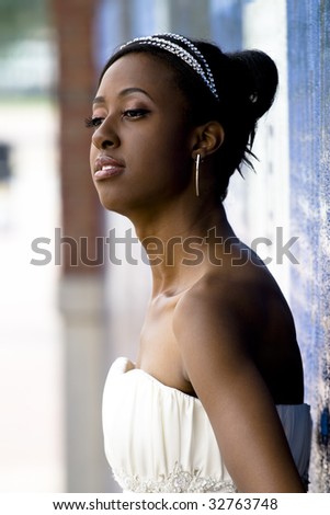 African American model wearing wedding gown posed against colorful wall.