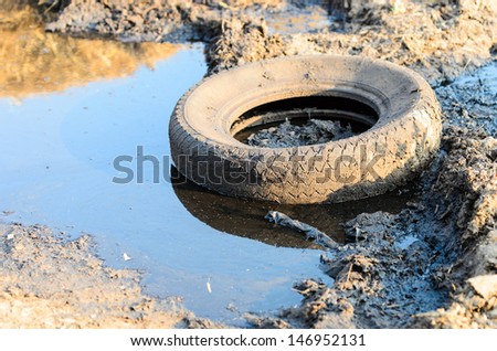A discarded old tyre in a puddle of contaminated water