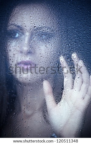 Girl watching through the window after a rain. Portrait.