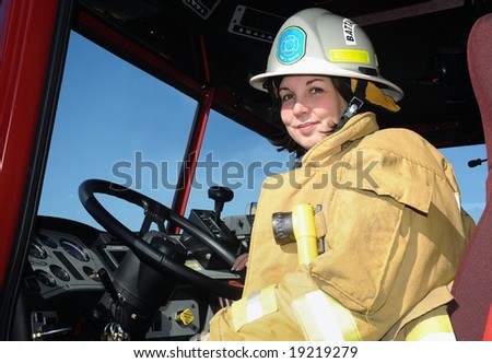 woman in cab of firetruck wearing turnout gear and helmet
