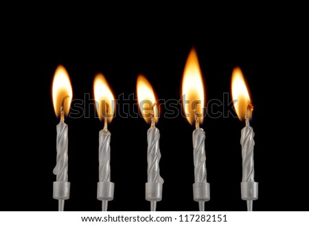 Five silver burning candles on black background