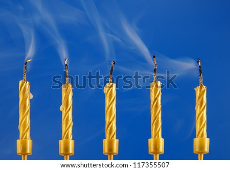 Five golden candles with smoke on blue background