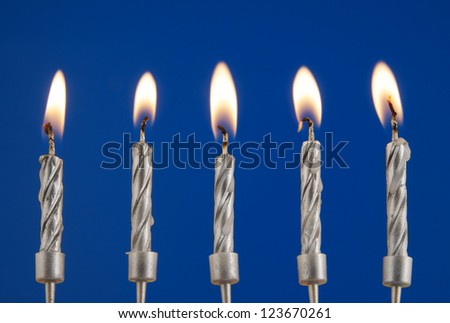 Five silver burning candles on blue background