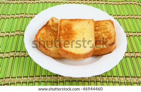 Fresh toasts on white plate on bamboo background