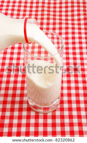 Pouring milk in a glass on checked tablecloth