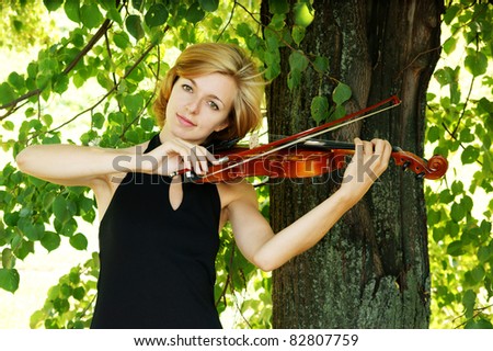 Pretty young woman playing the violin outdoor