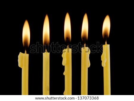 Yellow burning candles isolated on black background