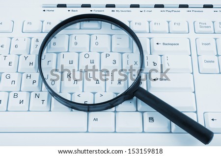 Magnifying glass on white keyboard close up