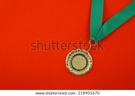 Gold medal with green ribbon on red velveteen with room for text