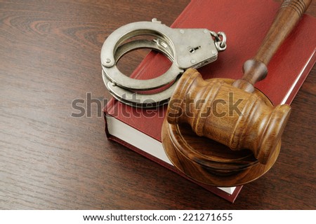 Judge\'s gavel and handcuffs on red legal book