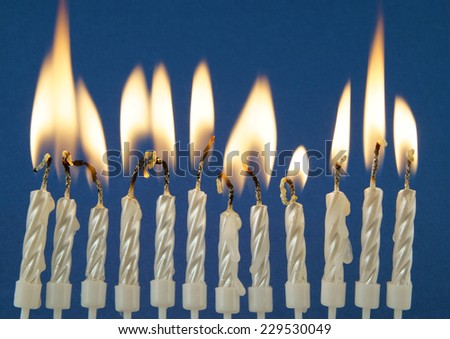 Twelve silver burning candles on blue background