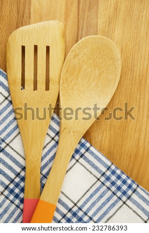 Tablecloth, spatula and spoon on wooden table background, cooking concept