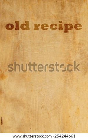 Old grunge wooden kitchen cutting board as background with words old recipe