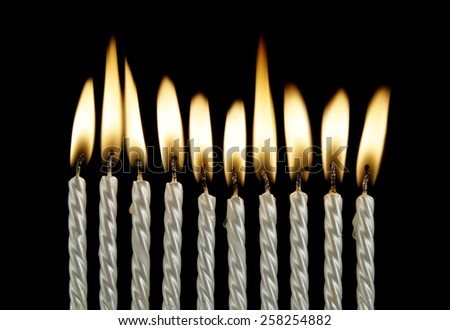 Ten silver burning birthday candles on black background