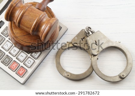 Wooden gavel, calculator and handcuffs on white table. financial fraud concept