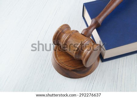Judge\'s wooden gavel and blue legal book on white table