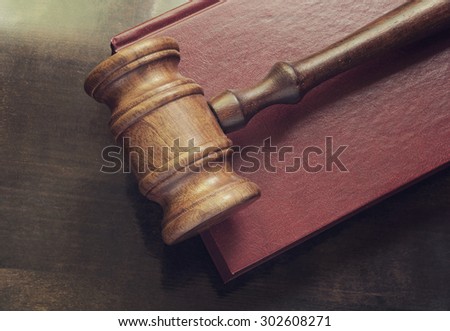 Wooden judge gavel and red legal book on wooden table