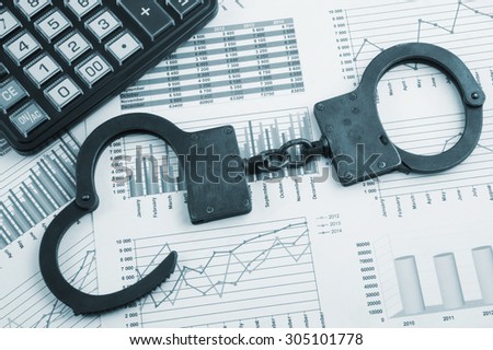 Financial fraud concept, calculator and handcuffs on financial documents