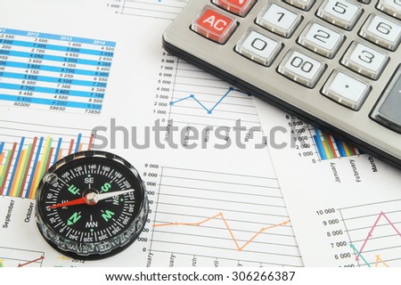 Navigation in financial world concept, calculator and compass on financial charts and graphs