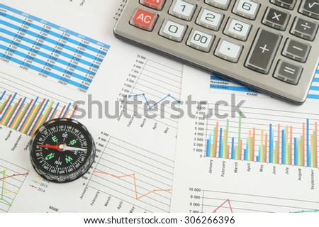 Navigation in financial world concept, calculator and compass on financial charts and graphs