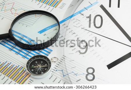 Navigation in financial world concept, magnifying glass and compass on financial charts and graphs