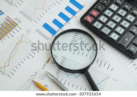 Business concept with charts, graphs, calculator, magnifying glass, pen and pencil