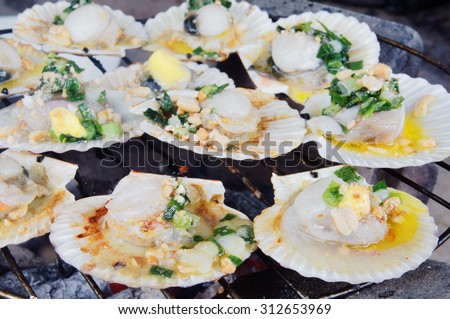 Barbecue grill cooking seafood, grilling scallops with butter onion and nuts