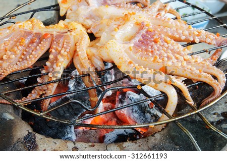 Cooking seafood barbecue, BBQ grilled squid on grid of old stone owen
