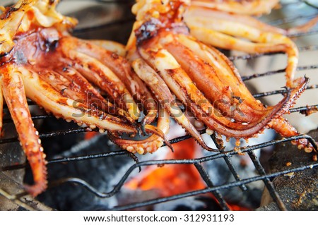 Cooking seafood barbecue, BBQ grilled squid on grid of old stone owen