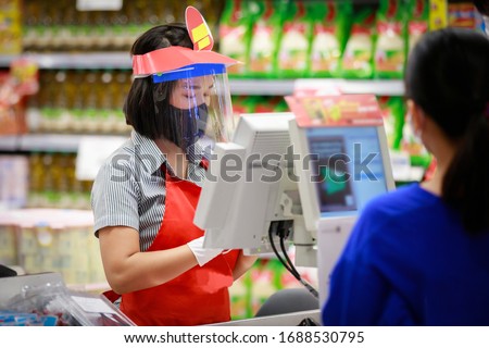 Cashier or supermarket staff in medical protective mask and face shield working at supermarket. covid-19 spreading outbreak  