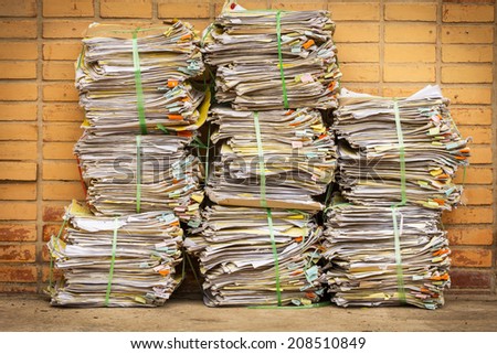 old document piles tied with plastic rope on brick background