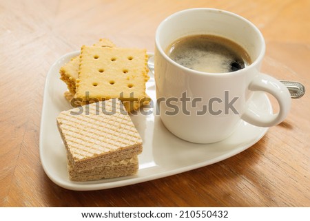 Cup of coffee and biscuit on wooden table