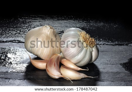 Closeup of organic garlic and garlic cloves on a black slate. Clean eating