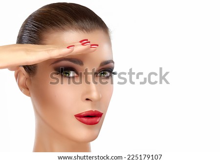Beautiful girl with fashion makeup and manicure doing a military salute. Yes sir!! Perfect skin, matte red lips, red nails and professional makeup. Beauty portrait isolated on white with copy space.