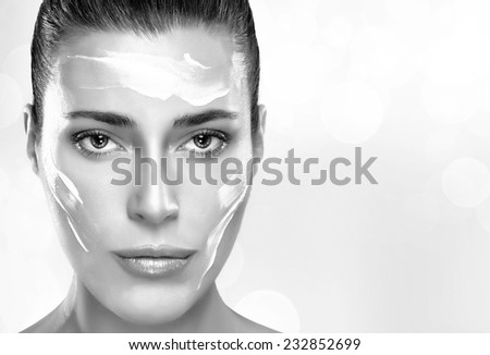 Beautiful healthy young woman with moisturizer in her clean face, close-up portrait in black and white. Skin care concept. Spa Treatment