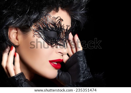 Masquerade. Pretty short hair gorgeous woman wearing elegant black mask and trendy mittens. Sexy lips and nails. Beauty and makeup concept. High fashion portrait isolated on black with copy space