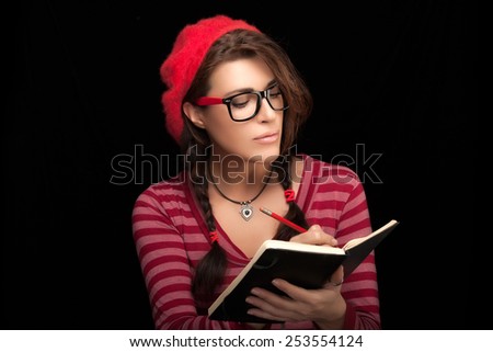 Close up Beautiful College Girl in Trendy Outfit Writing on her Notebook. Isolated on Black Background with Copy Space