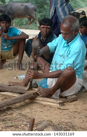 TAMIL NADU, INDIA, circa 2009: Unidentified Carpenter dressing beams for roof of school, circa 2009 in Tamil Nadu, India. Much of India\'s economy still relies on hand tools and skilled tradesmen.