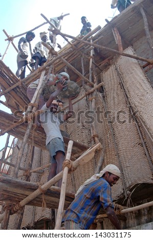 TAMIL NADU, INDIA, circa 2009: Unidentified men pass up bowls of cement at a construction site, circa 2009 in Tamil Nadu, India. India's economy relies on hand tools and skilled tradesmen.