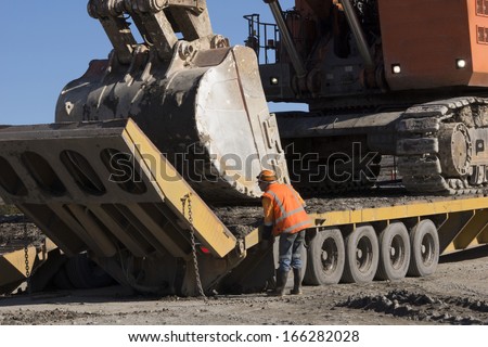 WESTPORT, NEW ZEALAND, AUGUST 31, 2013: An unidentified man adjusts the loading ramp on a loader to transport a 190 ton digger at an open cast coal mine on August 31, 2013 near Westport, New Zealand