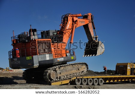 WESTPORT, NEW ZEALAND, AUGUST 31, 2013: Unidentified man directs a 190 ton digger onto a 48 wheel transporter at Stockton coal mine on August 31, 2013 near Westport, New Zealand.