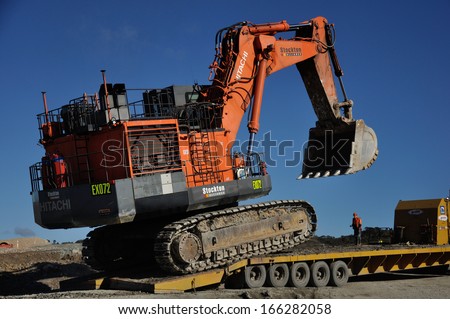 WESTPORT, NEW ZEALAND, AUGUST 31, 2013: Unidentified man directs a 190 ton digger onto a 48 wheel transporter at Stockton coal mine on August 31, 2013 near Westport, New Zealand.
